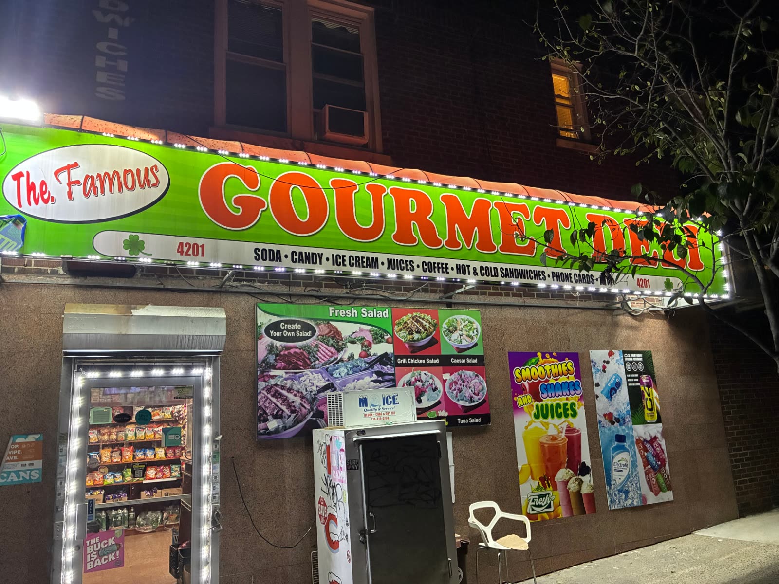The Famous Deli storefront with its lit green awning at 4201 Oneida Ave in the Bronx